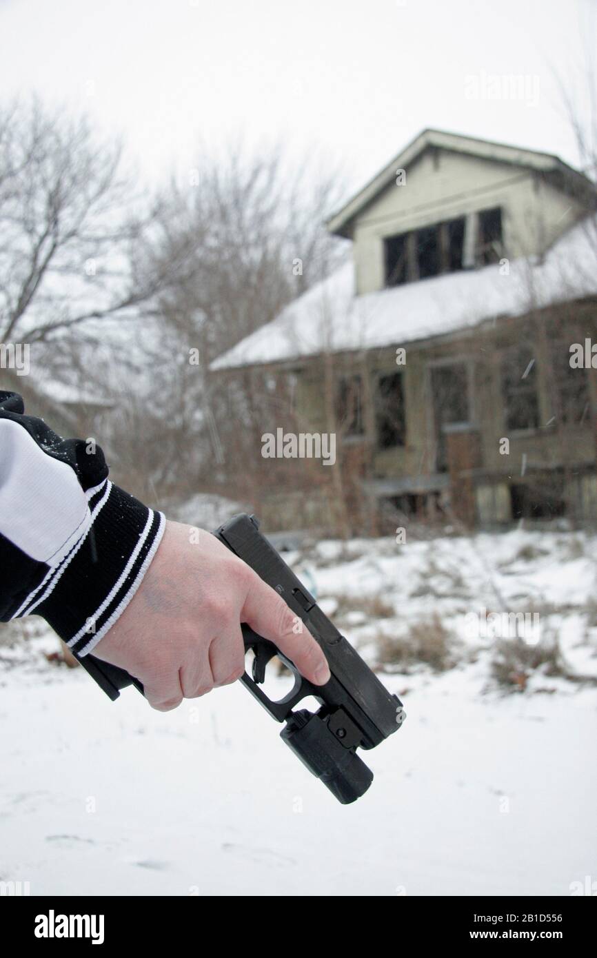 Uomo che tiene la pistola Glock sulla strada coperta di neve a Detroit, Michigan, Stati Uniti Foto Stock