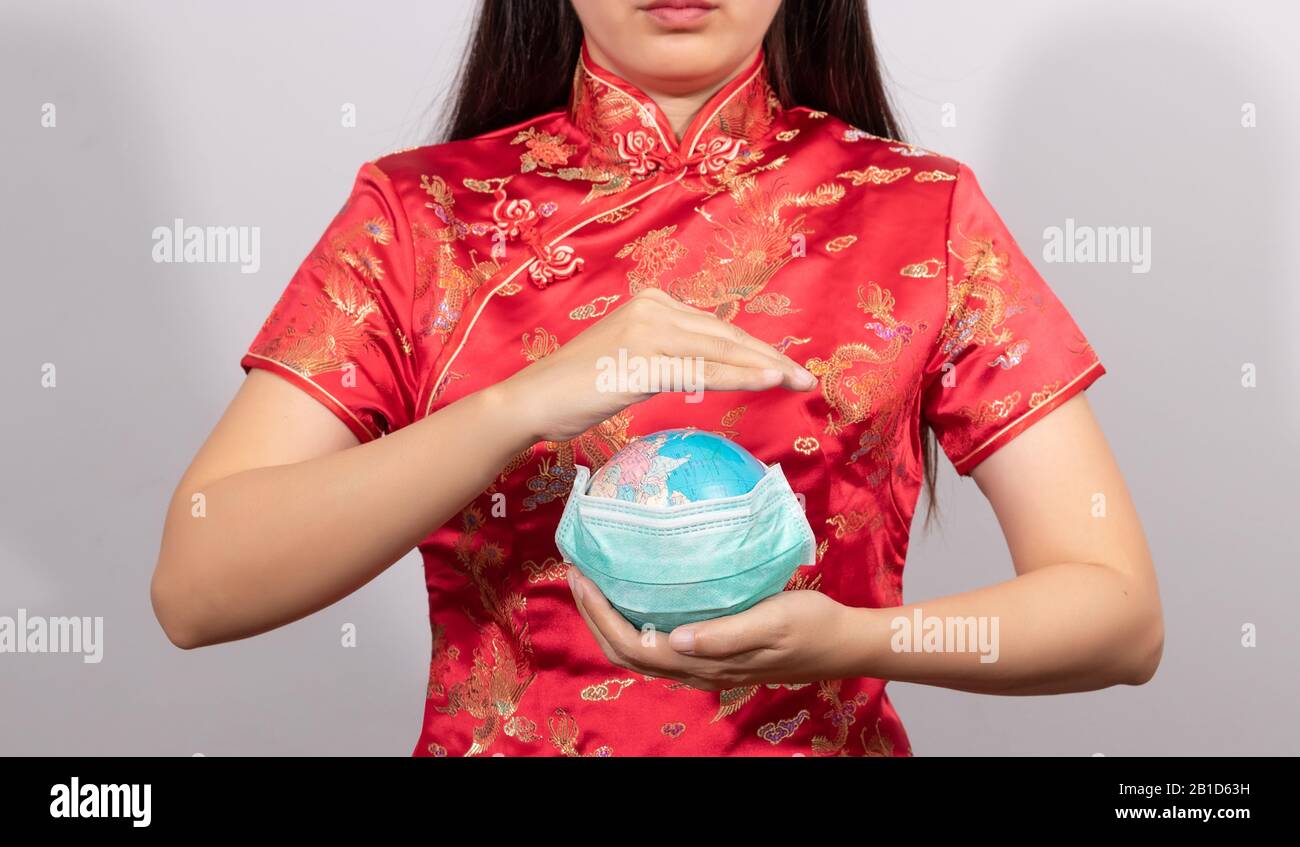 Donna asiatica in costume cinese tenere globo indossare una maschera igienica in mano per prevenire i gesti. Malattia del mondo da scoppio situazione di Coronavirus 2 Foto Stock