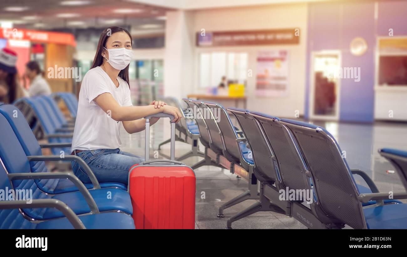 Turista asiatico con bagaglio, indossare maschera igienica per evitare durante il viaggio al terminal dell'aeroporto per proteggere dal Coronavirus 2019 (COVID-1 Foto Stock