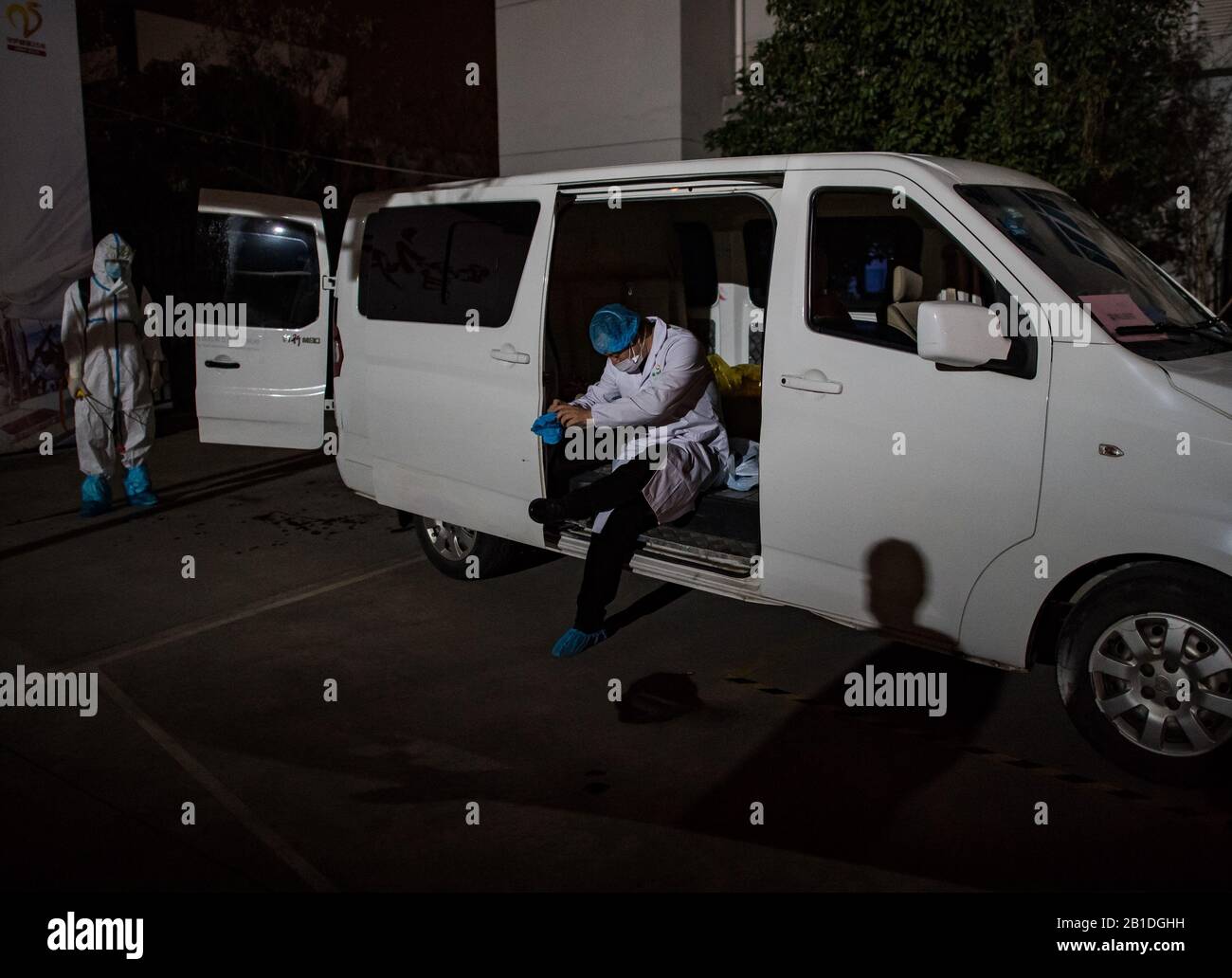 (200225) -- WUHAN, 25 febbraio 2020 (Xinhua) -- Liu Senbo (R) mette su un camice da laboratorio al suo arrivo in un centro di analisi dei virus a Wuhan, nella provincia centrale cinese di Hubei, 24 febbraio 2020. Liu Senbo, un veterano di 46 anni di Guangzhou, la provincia del Guangdong della Cina meridionale, è stato a Wuhan per aiutare il romanzo coronavirus a controllare gli sforzi dal 19 febbraio. Rivestito in tute protettive, ora lavora come un campione di paziente 'deliveryman.' recupera campioni prelevati da pazienti COVID-19 nell'ospedale di Leishenshan due volte al giorno, e li invia a un centro di test antivirus del Guangdong KingMed Diagnostics Group situato in W. Foto Stock