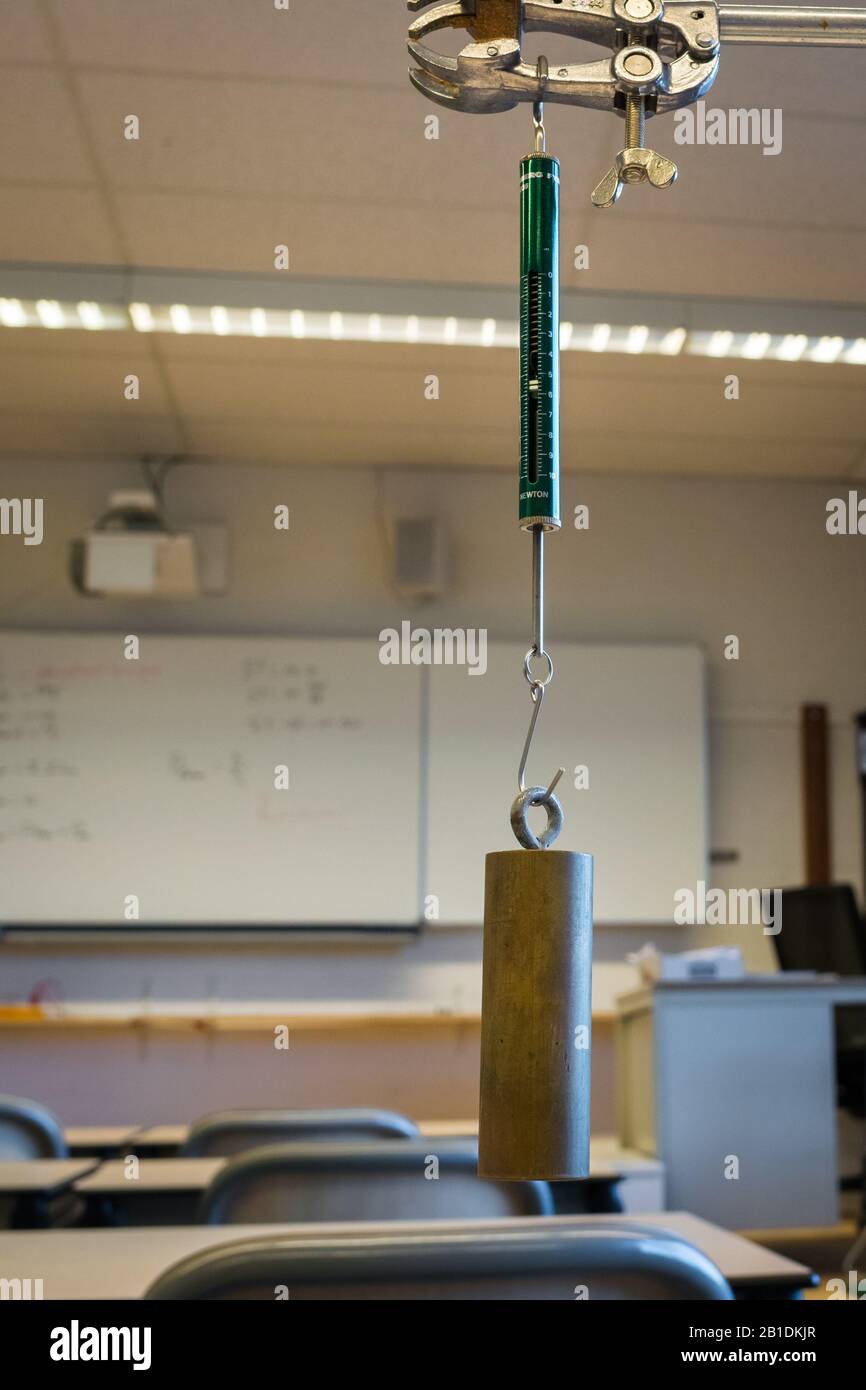 Peso sospeso sull'equilibratore a molla Newton per misurare la forza. Esperimento di fisica. Foto Stock Peso sospeso sull'equilibratore a molla Newton per misurare la forza. Esperimento di fisica. Foto Stock
