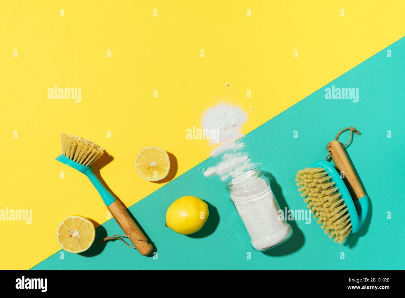 Bicarbonato di sodio, limone, polvere di senape e spazzole di bambù contro prodotti chimici domestici su sfondo giallo. Vista dall'alto. Spazio di copia. Disposizione piatta. Pulizia della casa efficace e sicura. Foto Stock
