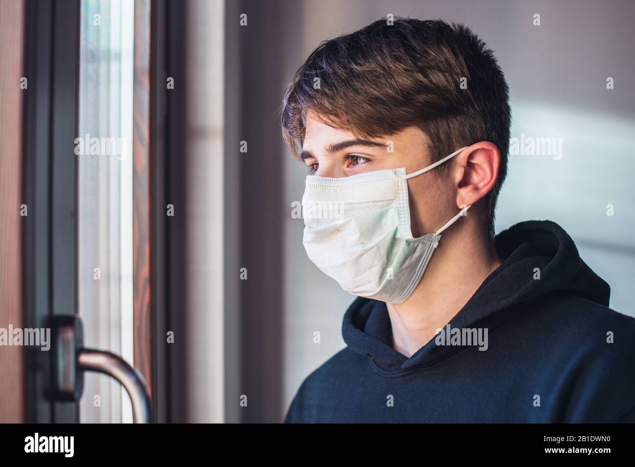 rimani a casa - ragazzo giovane con maschera protettiva - infezione paura concetto - quarantena a casa Foto Stock