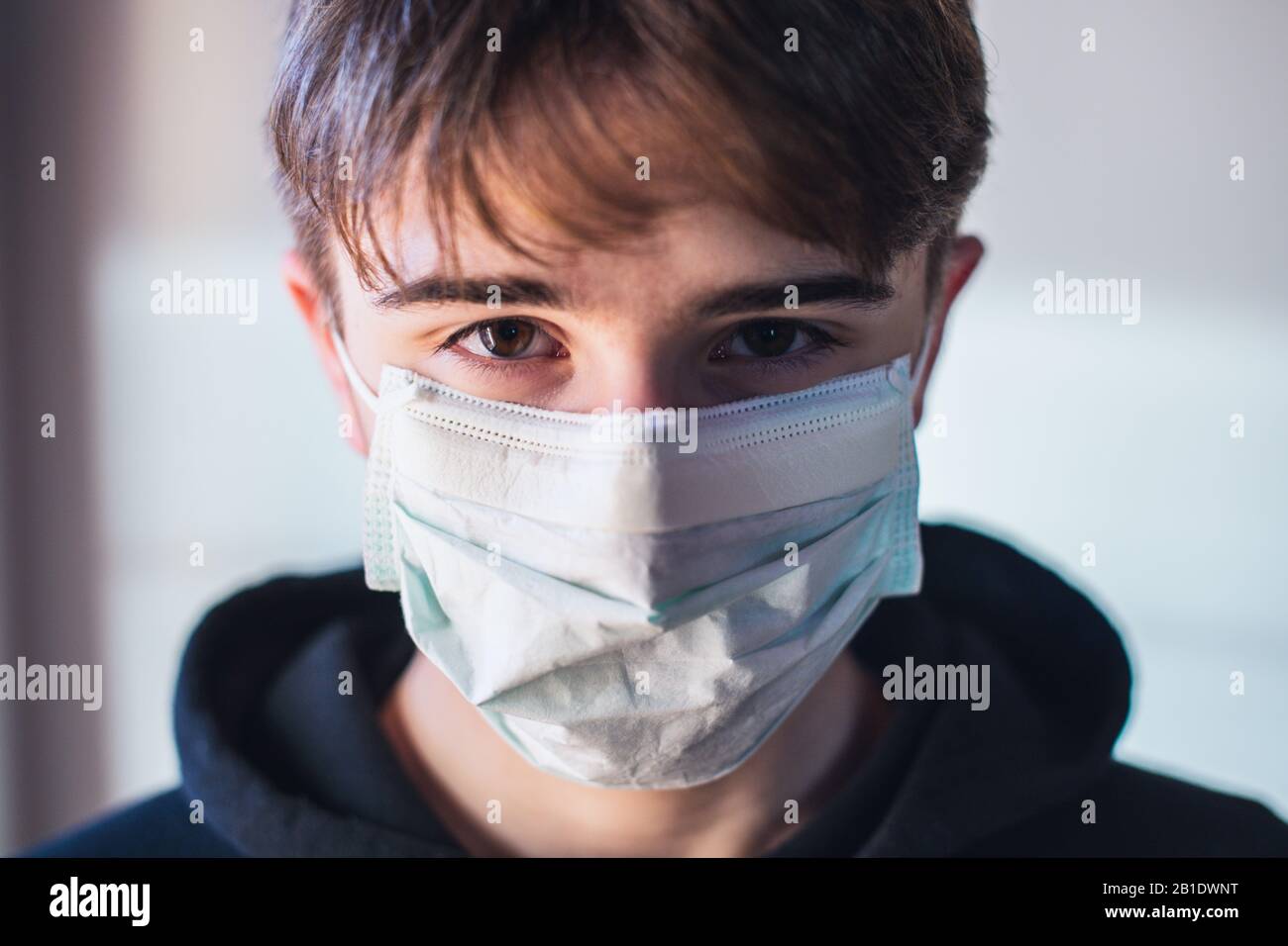 rimani a casa - ragazzo giovane con maschera protettiva - infezione paura concetto - quarantena a casa Foto Stock