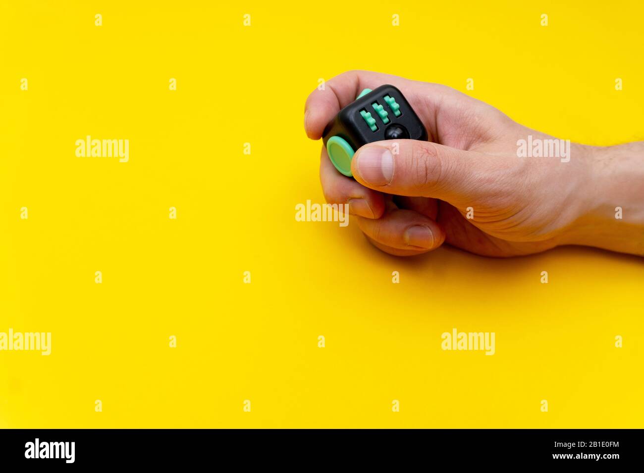 Antistress fidget in mans mano destra su sfondo giallo Foto Stock