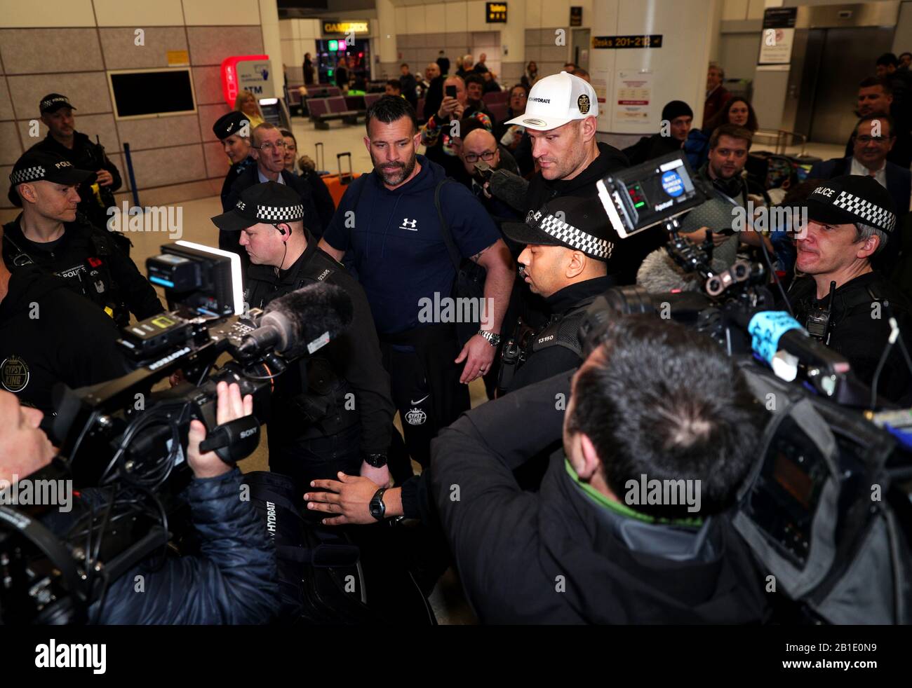 Tyson Fury è scortato attraverso la folla dalla sicurezza all'Aeroporto di Manchester. Foto Stock