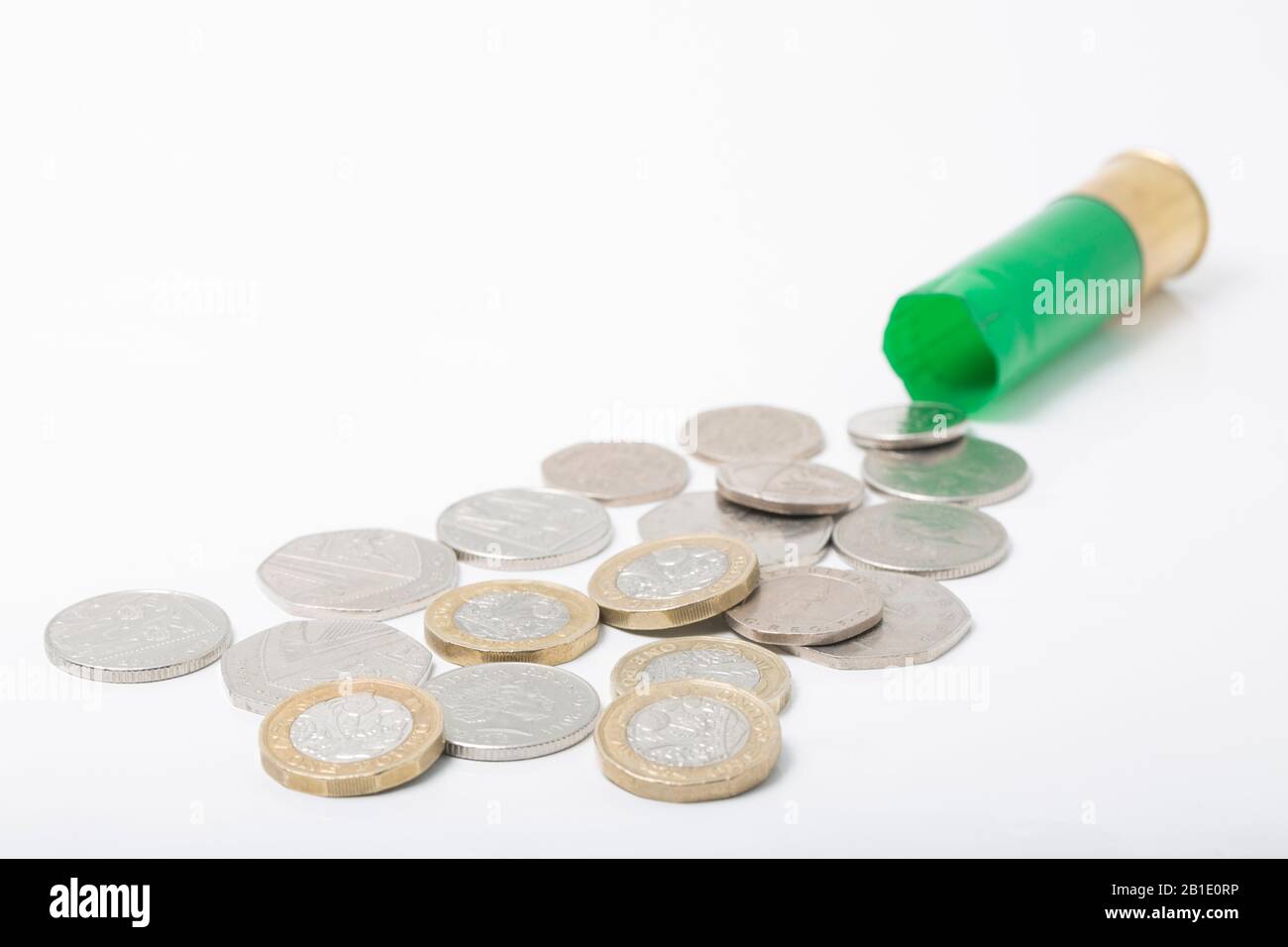 Un'immagine che mostra una cartuccia di fucile in plastica vuota/sparata con monete di vari valori. Concetto per mostrare il costo di munizioni e alternative a le Foto Stock