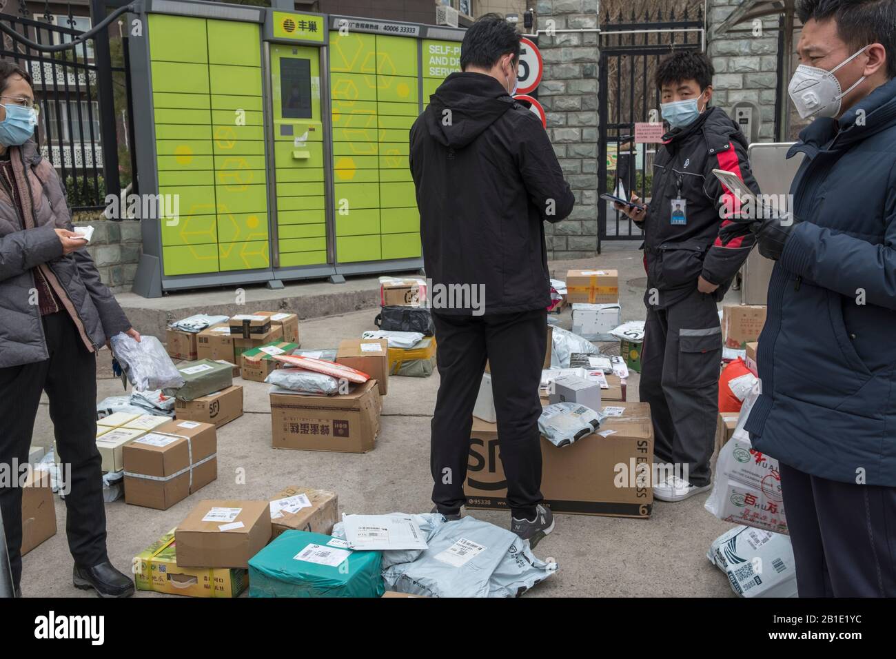 I clienti cinesi prelevano i pacchi da soli, in mezzo allo scoppio di un nuovo coronavirus, in un punto di servizio espresso temporaneo al di fuori di un re murato Foto Stock