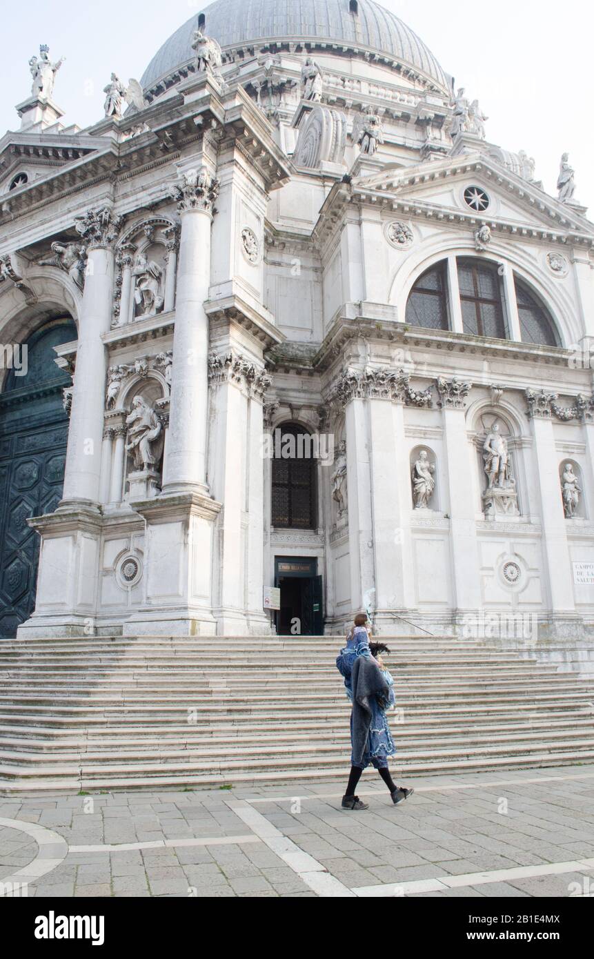 Padre e figlia in costume veneziano passeranno davanti alla Basilica di Santa Maria della Salute, Venezia, Italia Foto Stock