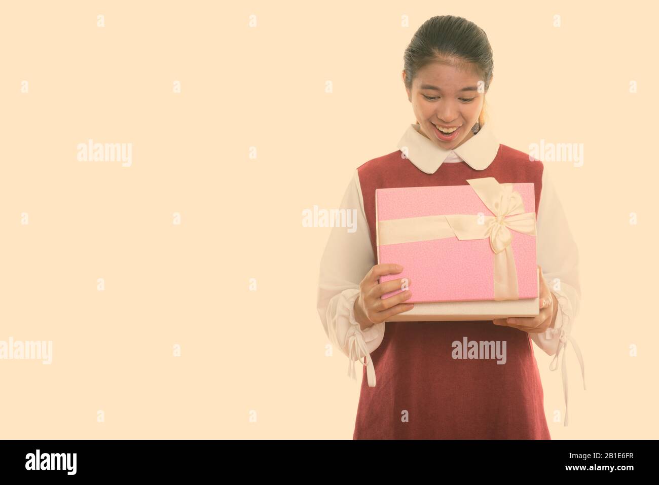 Studio scatto di giovane felice donna asiatica sorridente mentre apre scatola regalo Foto Stock