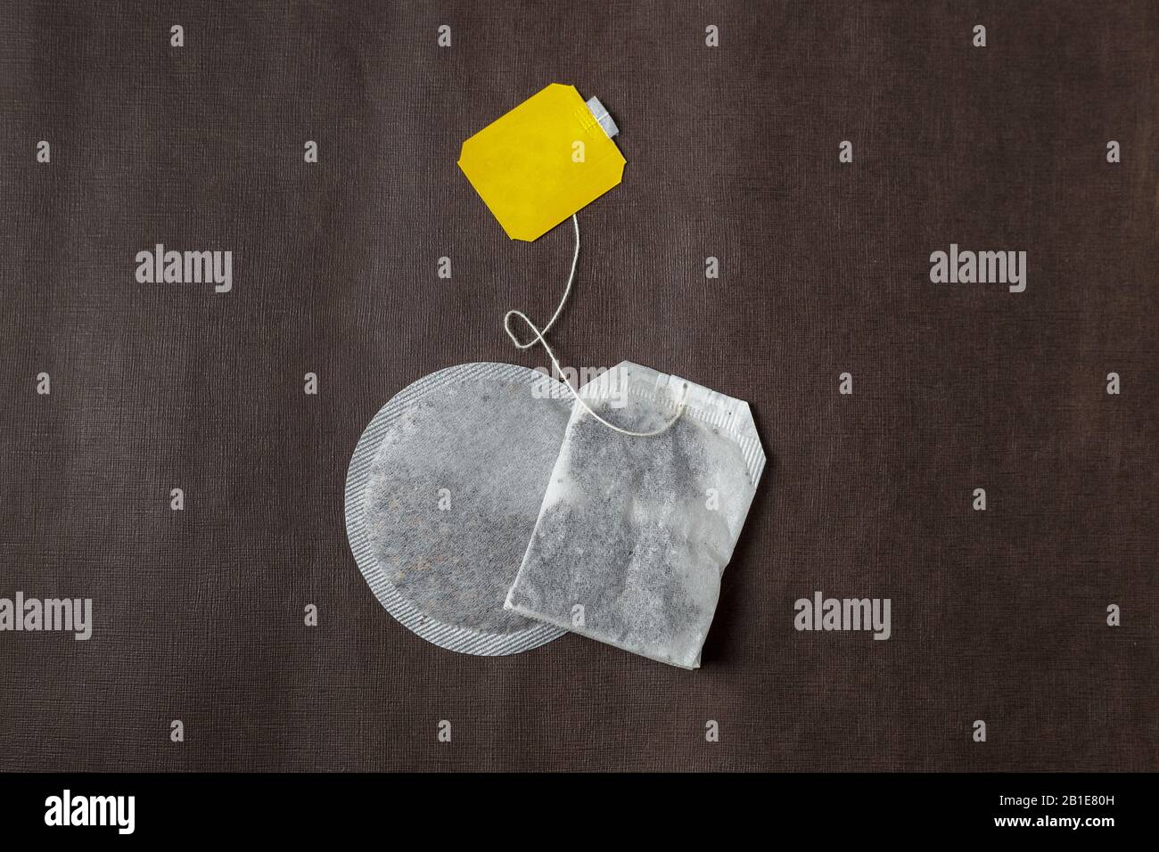 Teabags con etichetta gialla. Vista dall'alto, su sfondo marrone scuro. Mockup Foto Stock