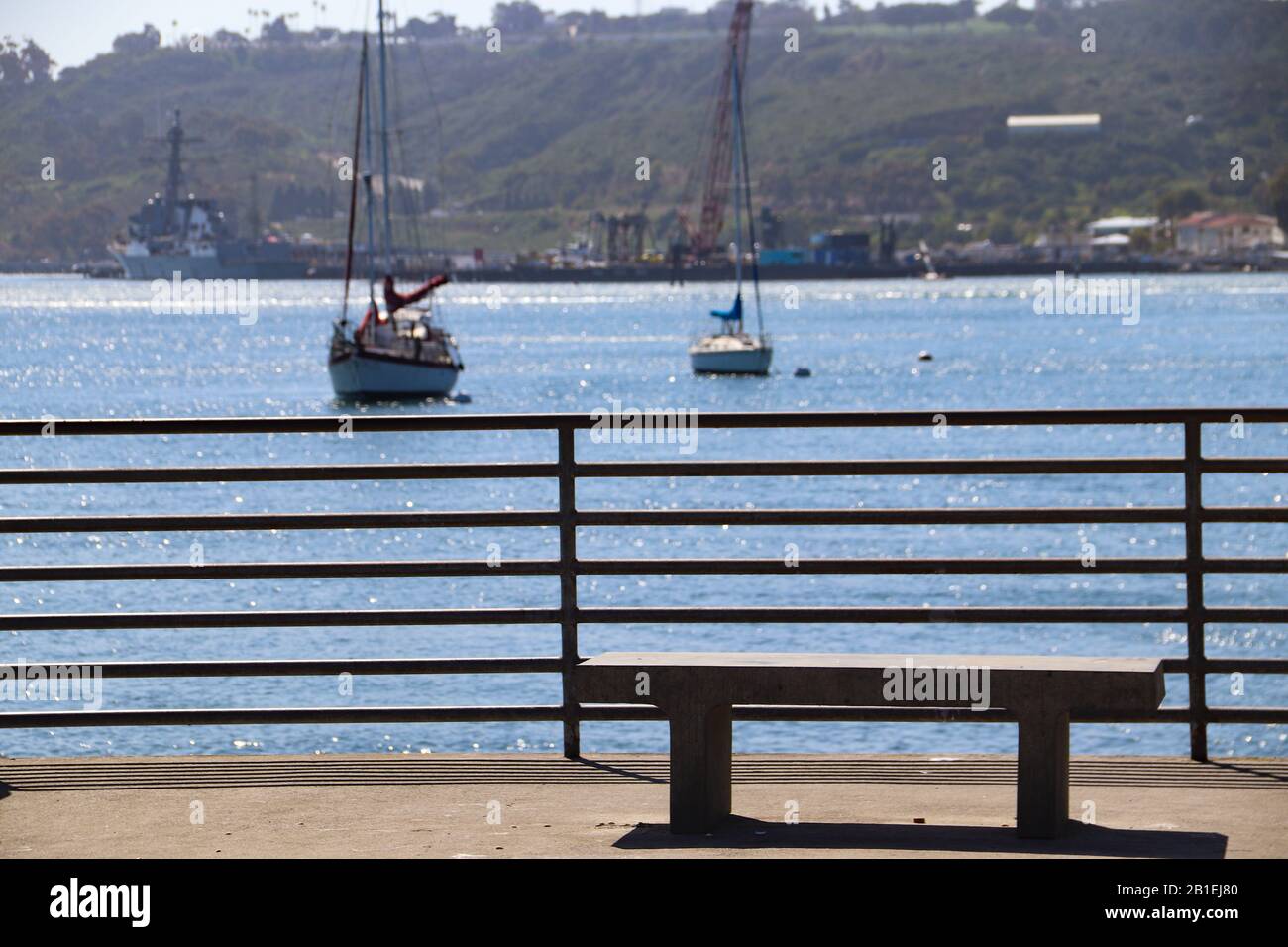 Panca vuota di cemento sul molo di pesca che si affaccia sulle barche a vela nella Baia di San Diego Foto Stock