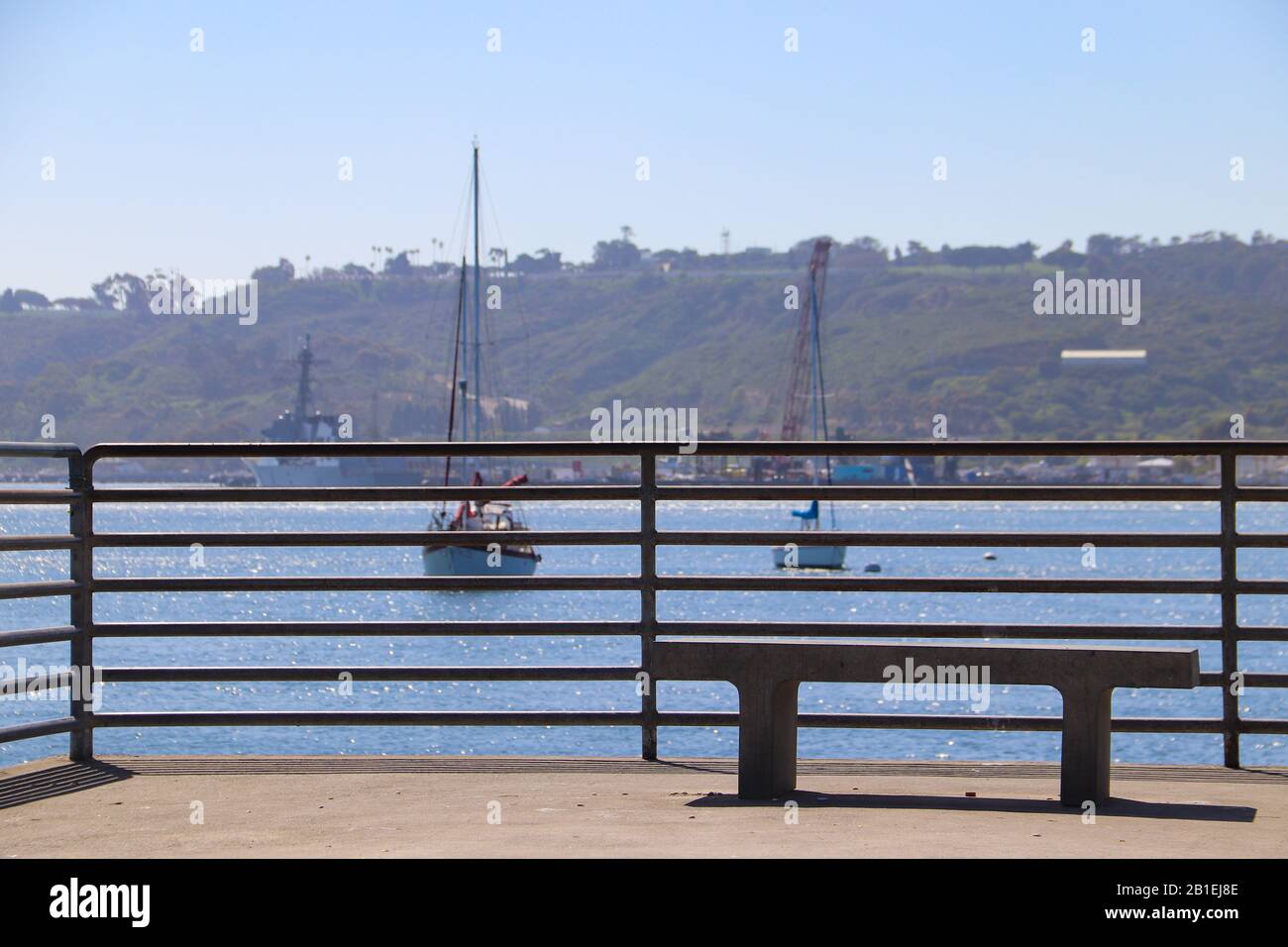 Panca vuota di cemento sul molo di pesca che si affaccia sulle barche a vela nella Baia di San Diego Foto Stock