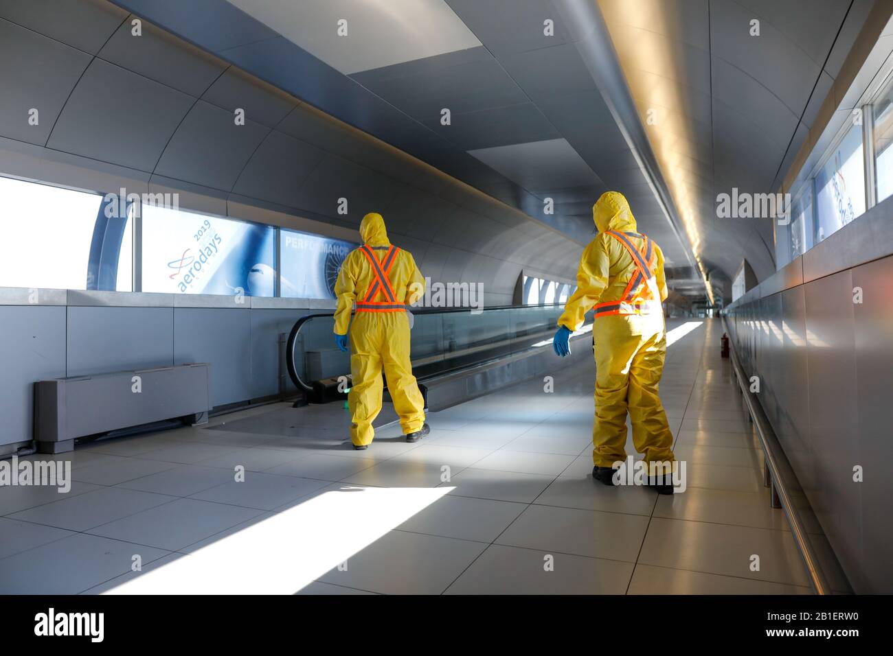 Otopeni, Romania - 25 febbraio 2020: Persone che indossano tute protettive spray disinfettante sostanze chimiche sull'aeroporto internazionale Henri Coanda per dare il meglio di sé Foto Stock