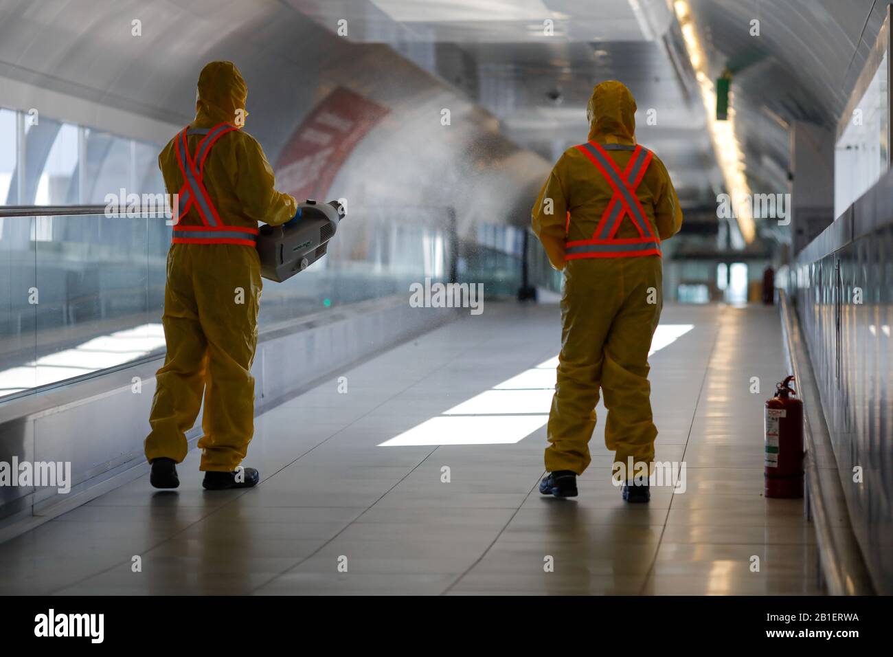 Otopeni, Romania - 25 febbraio 2020: Persone che indossano tute protettive spray disinfettante sostanze chimiche sull'aeroporto internazionale Henri Coanda per dare il meglio di sé Foto Stock