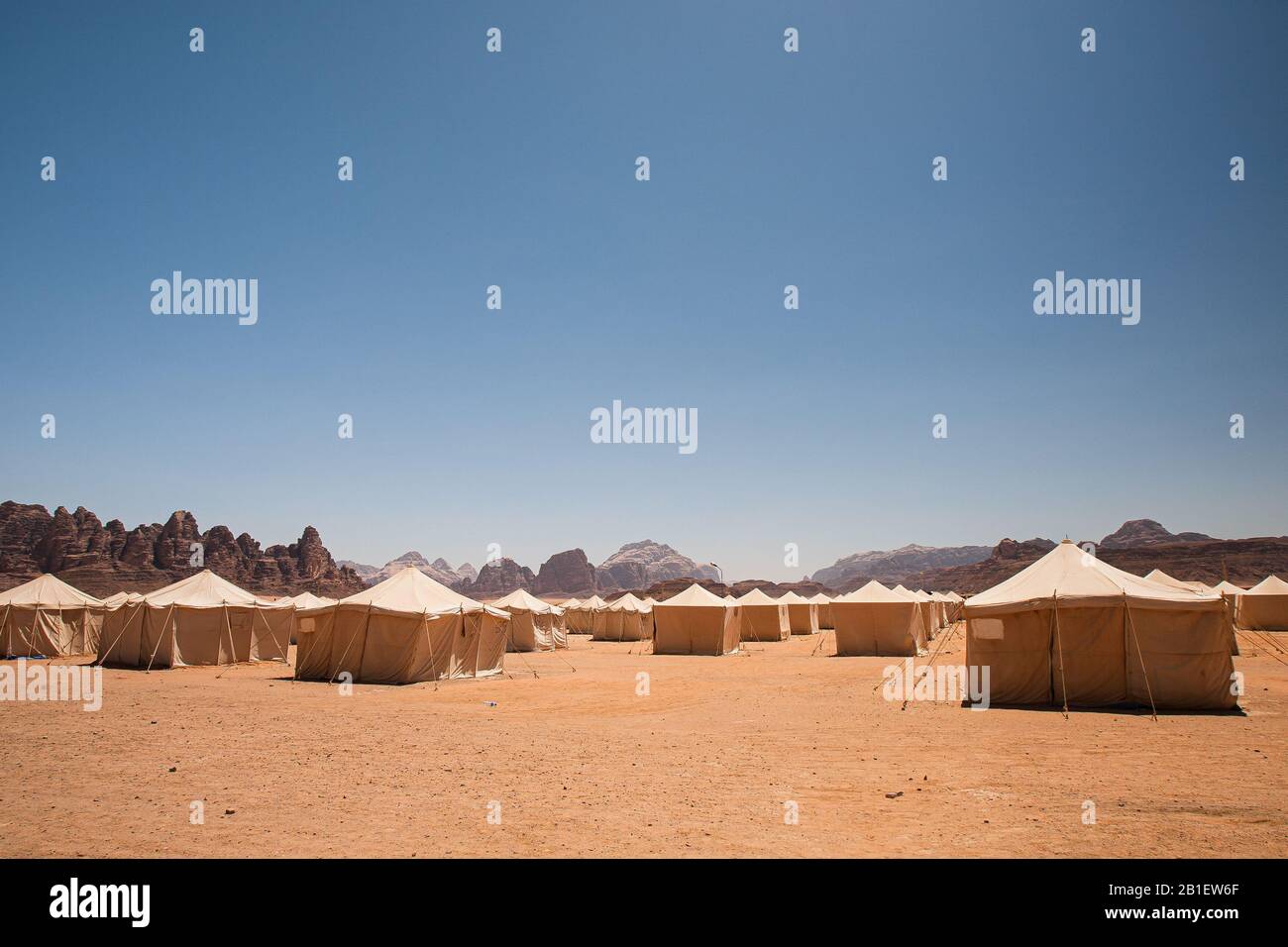 Infinite file di tende bianche nel deserto, circondate da montagne rocciose, nel campo Jabal Rum di Wadi Rum, Giordania. Foto Stock