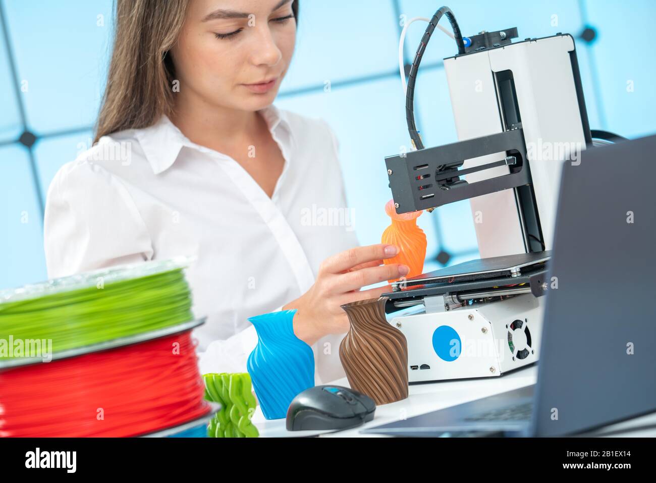 Giovane designer femminile lavora con una stampante 3D in uno studio di design Foto Stock