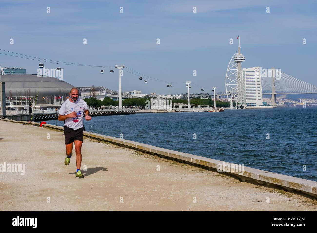 uomo che corre all'aperto vicino al fiume tago con vaso da gama torre dietro a lisbona portogallo Foto Stock