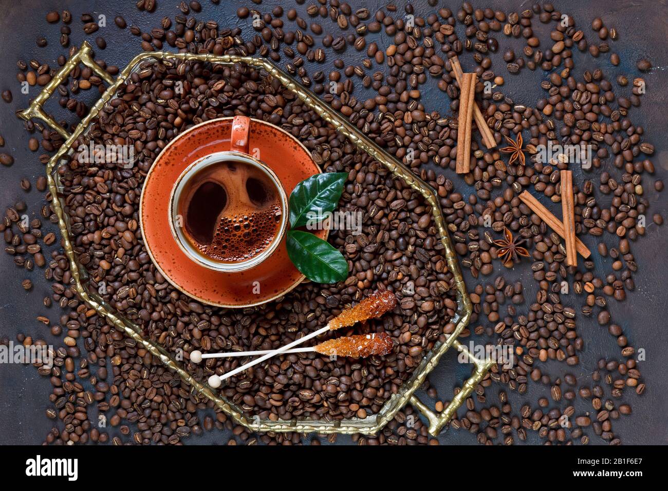 Una tazza di caffè sul vassoio con chicchi di caffè sullo sfondo nero del tavolo. |Vista dall'alto, primo piano. Foto Stock