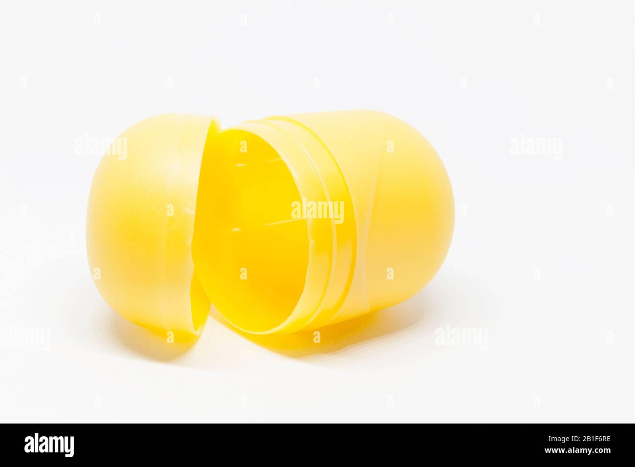 un uovo giocattolo giallo aperto su sfondo bianco Foto Stock