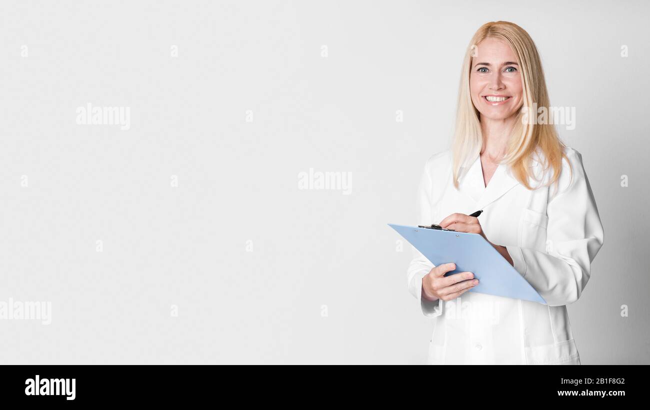 La donna di mezza età che tiene gli appunti che scrivono la diagnosi Foto Stock