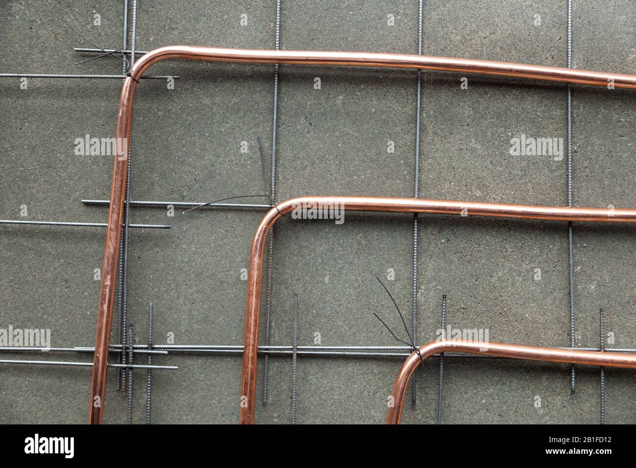 Primo piano nuovo tubo in rame lucido piegato a pavimento, posa tubazioni,  installazione tubi a pavimento con riscaldamento a caldo dell'appartamento,  vista dall'alto, orizzontale Foto stock - Alamy