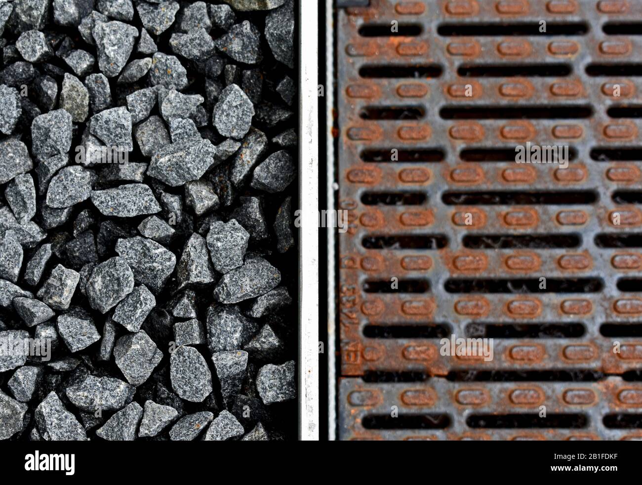 Pioggia arrugginita di metallo arrugginita accanto alla ghiaia grigia, contrasto Foto Stock