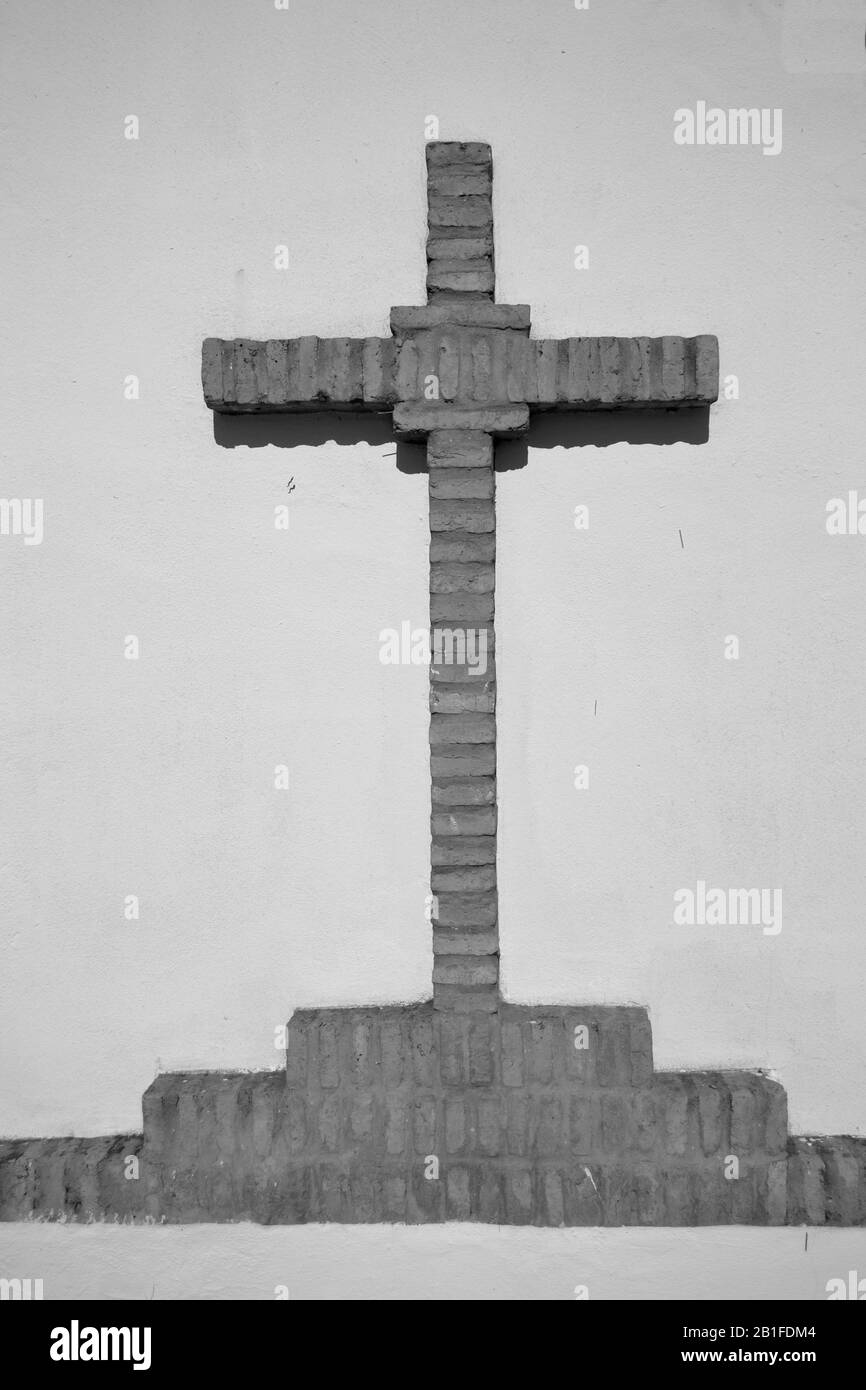 Croce cristiana di mattoni in bianco e nero su sfondo bianco in un recinto per celebrare Romerias in campagna Foto Stock