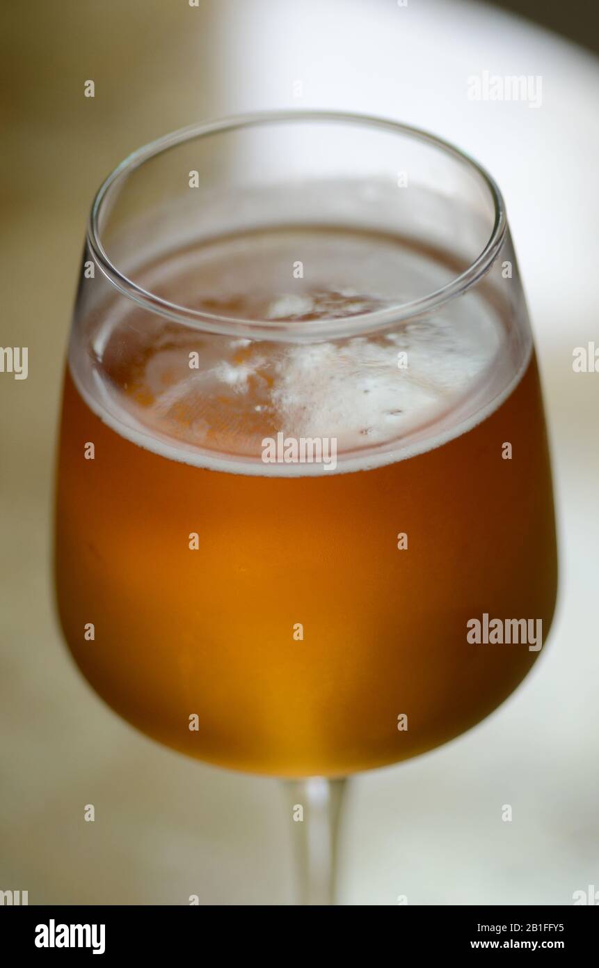 BREW HOUSE: Un primo piano di un bicchiere freddo di birra con acqua di condensazione che gocciola lateralmente e bolle gassate che si innalzano con una parte superiore gelida. Foto Stock