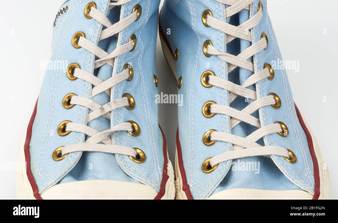 frammento di sneaker blu con lacci in tessuto bianco su sfondo bianco, primo piano Foto Stock