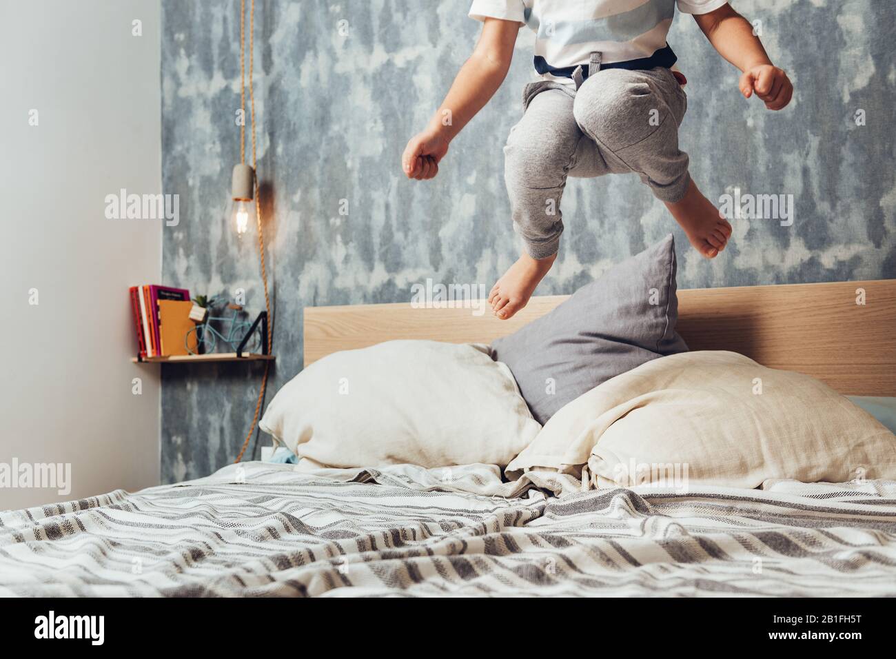 dettaglio di una piccola ragazza gambe saltando in alto nel suo letto genitori, concetto di stile di vita a casa e infanzia felice Foto Stock