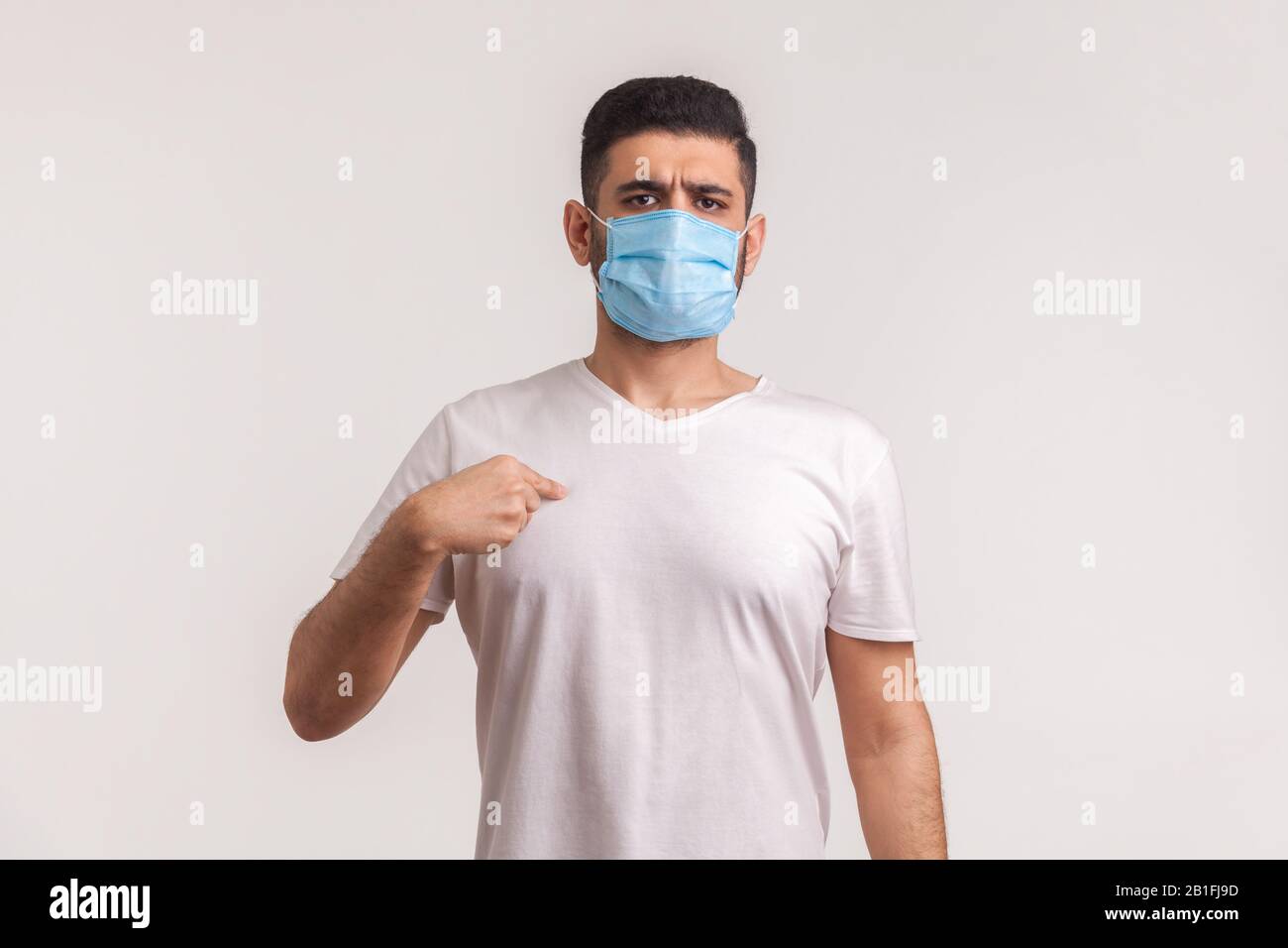 Uomo nella maschera chirurgica che punta se stesso, indossando un filtro protettivo per prevenire l'infezione da coronavirus, malattie respiratorie aeree come l'influenza, 2019-nCoV Foto Stock