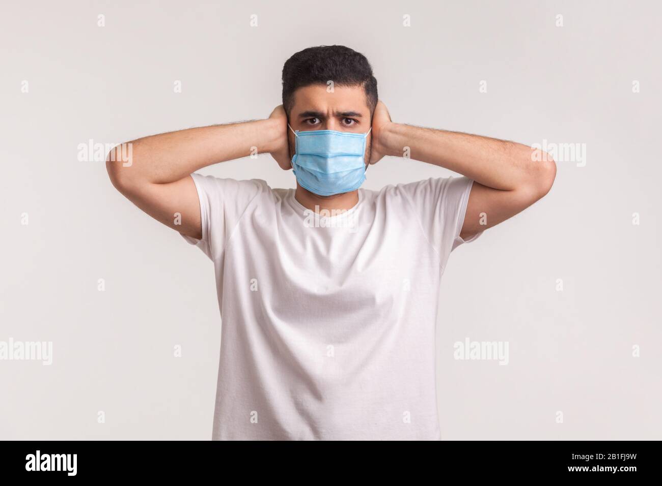 Protezione contro il coronavirus, malattia contagiosa. Uomo che copre le orecchie e indossa una maschera igienica di sicurezza per prevenire infezioni, malattie respiratorie come Foto Stock