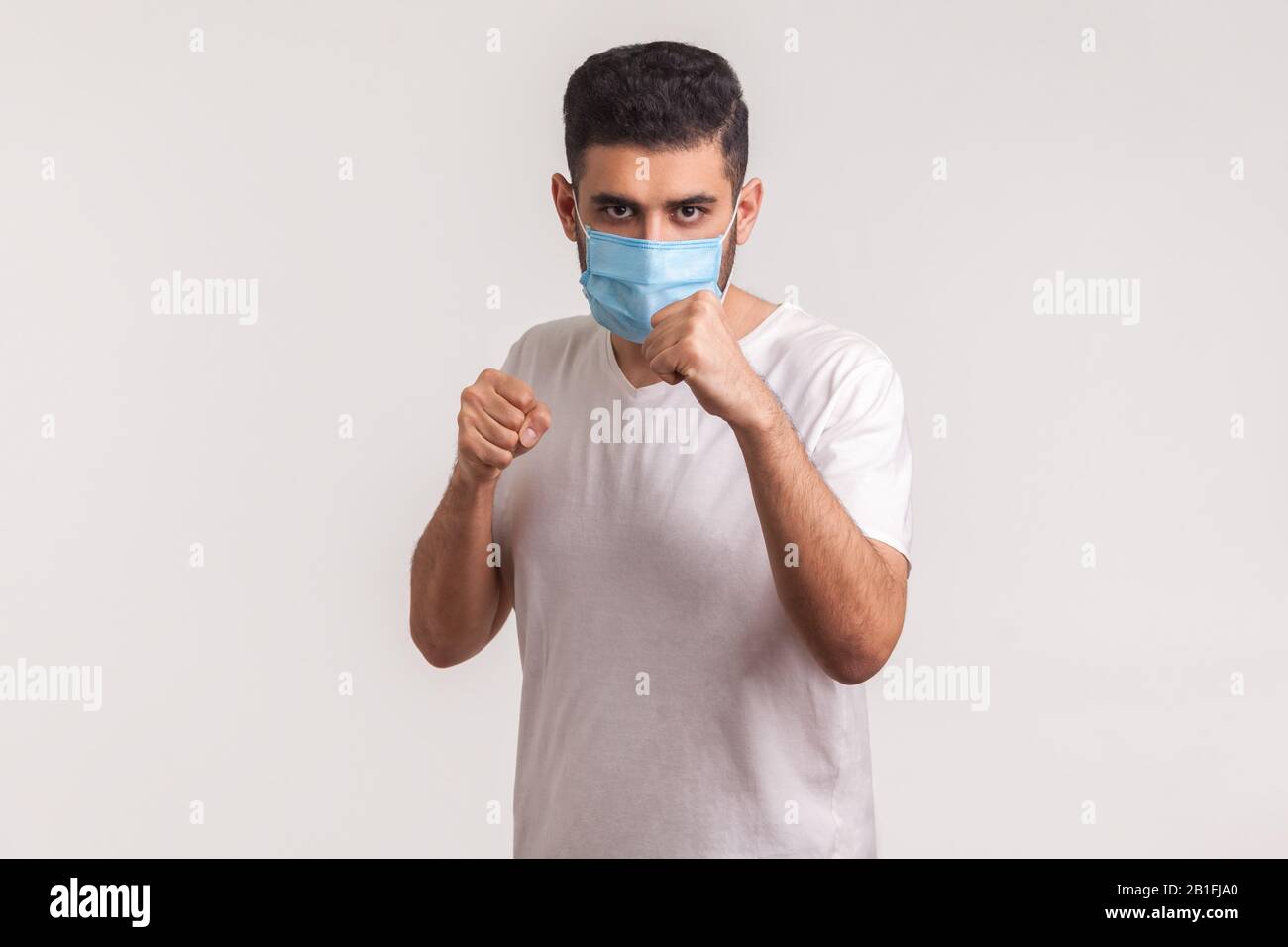 Uomo in maschera chirurgica pugilato alla telecamera, lotta contro malattie contagiose, infezione da coronavirus, malattie respiratorie come l'influenza, 2019-nCoV Foto Stock