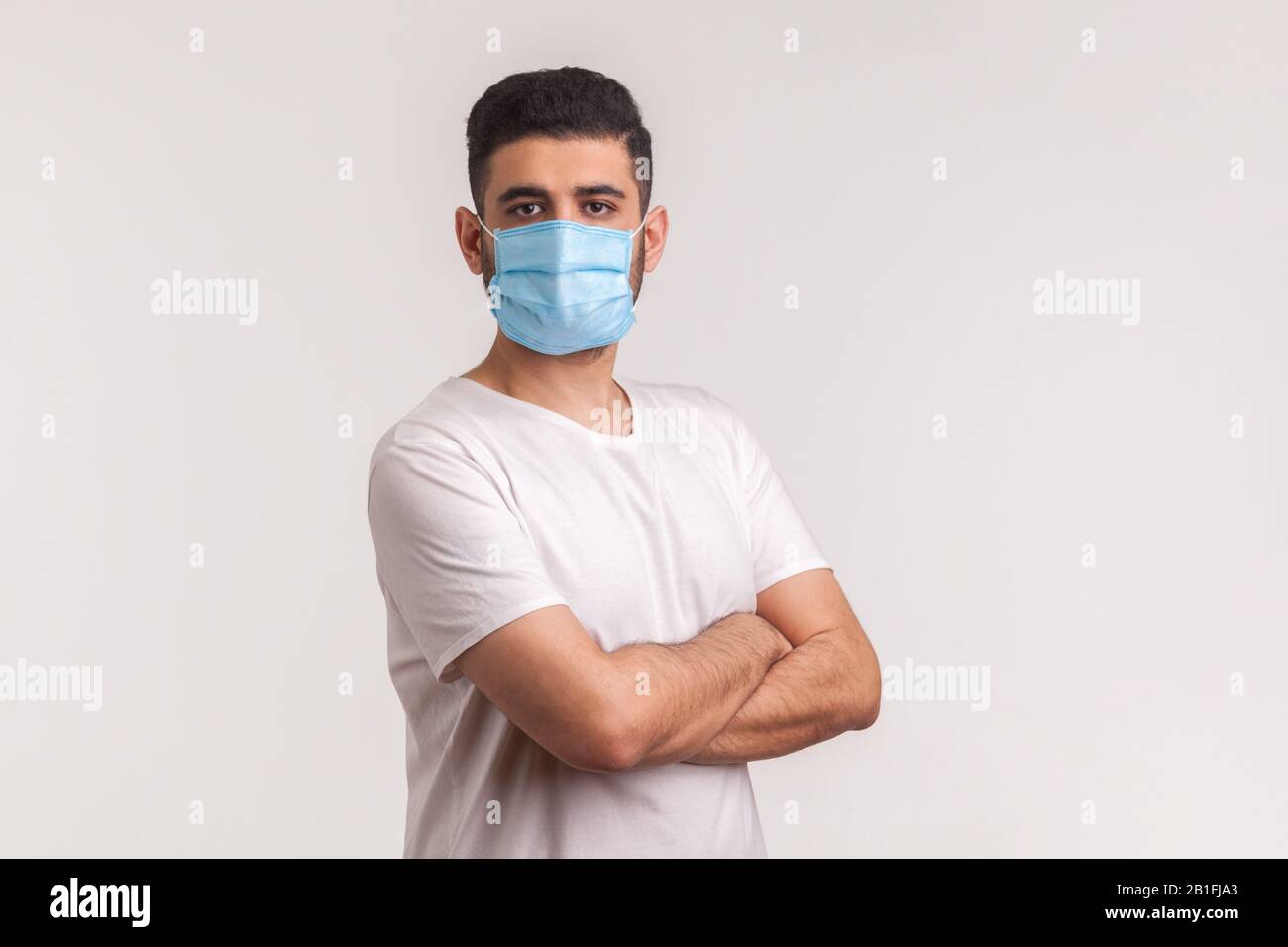 Protezione efficace contro il coronavirus. Uomo che tiene le mani incrociate e che indossa maschera igienica per prevenire l'infezione, malattie respiratorie come l'influenza, 2 Foto Stock