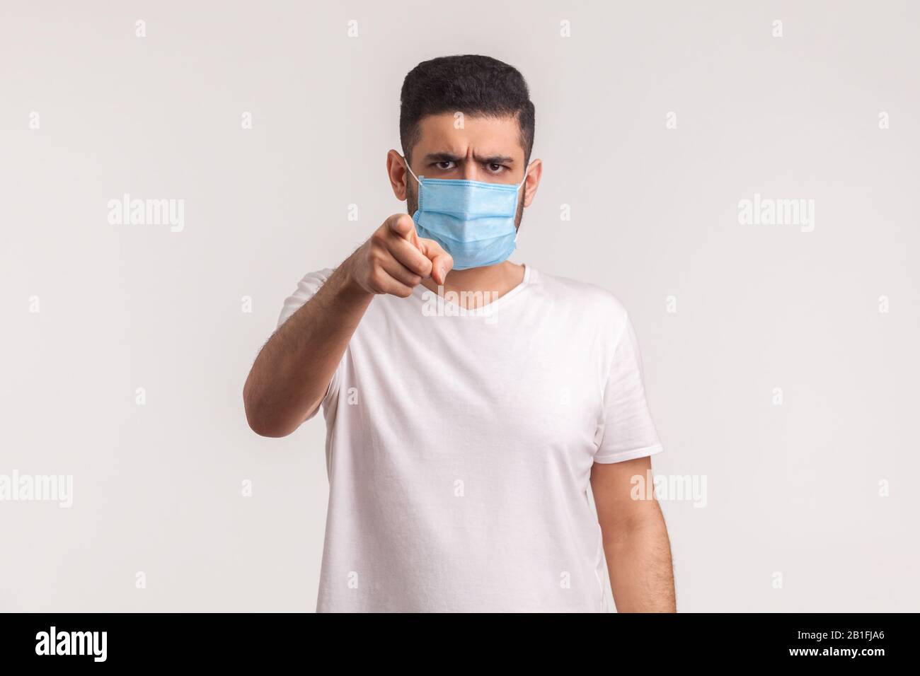 Ehi, usi i filtri contro l'influenza nuova! Uomo che punta alla fotocamera e indossa maschera igienica per prevenire infezioni da coronavirus, malattie respiratorie Foto Stock