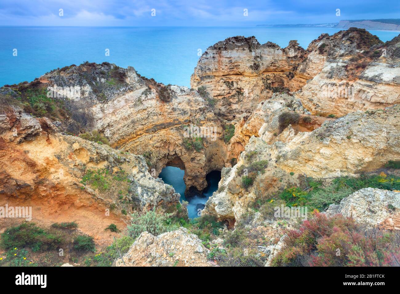 Alba nuvoloso alle scogliere gialle e rosse di Ponta da Piedade con una grotta a forma di cuore. Lagos, Algarve, Portogallo, Europa. Foto Stock