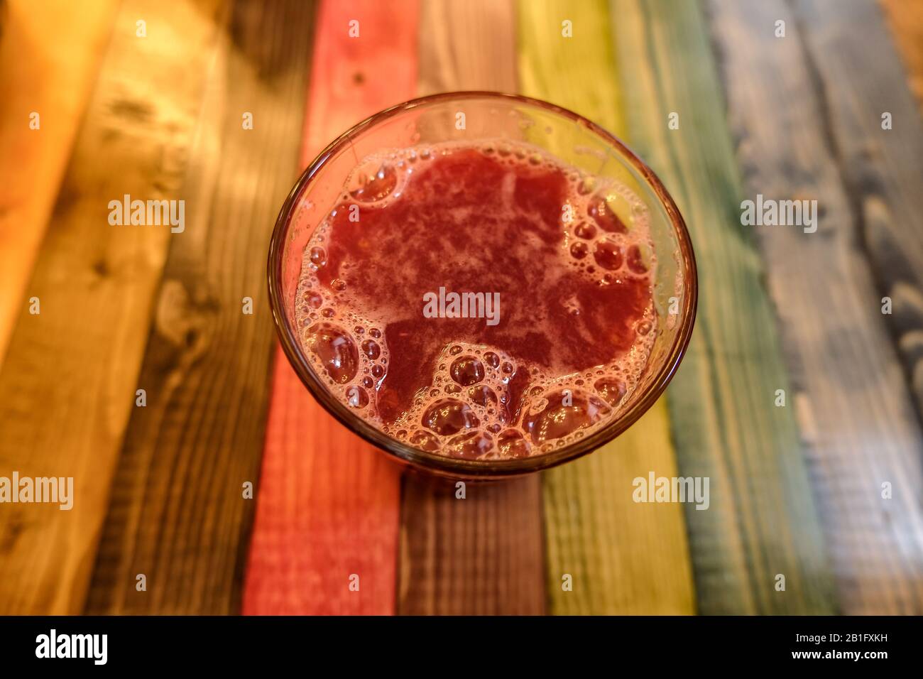 Melograno gustoso succo su sfondo multicolore, genuine bevande fresche d'estate Foto Stock