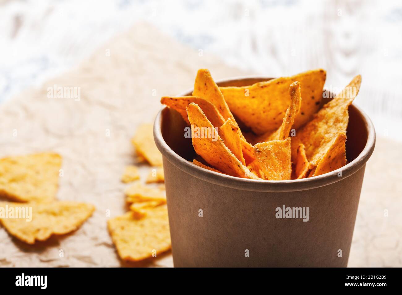 Tortilla patatine in ciotola di carta artigianale su tavola di legno rustica, primo piano Foto Stock