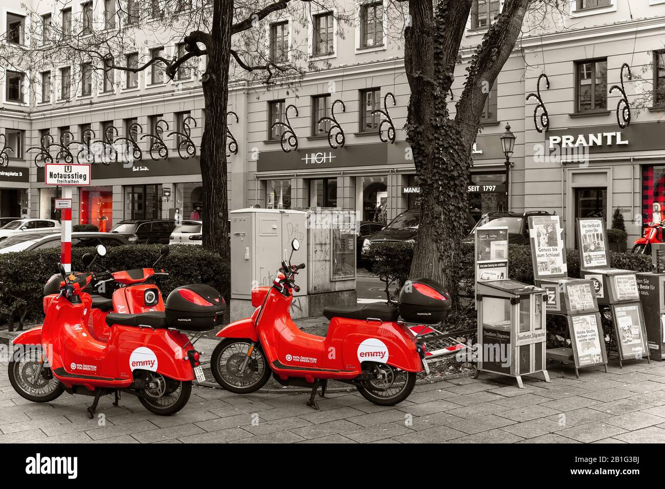 Monaco/GERMANIA - Gennaio 2020 scooter elettrici rossi da noleggiare sulla strada nel centro di Monaco. Parcheggiava le auto e le finestre del negozio come sfondo Foto Stock