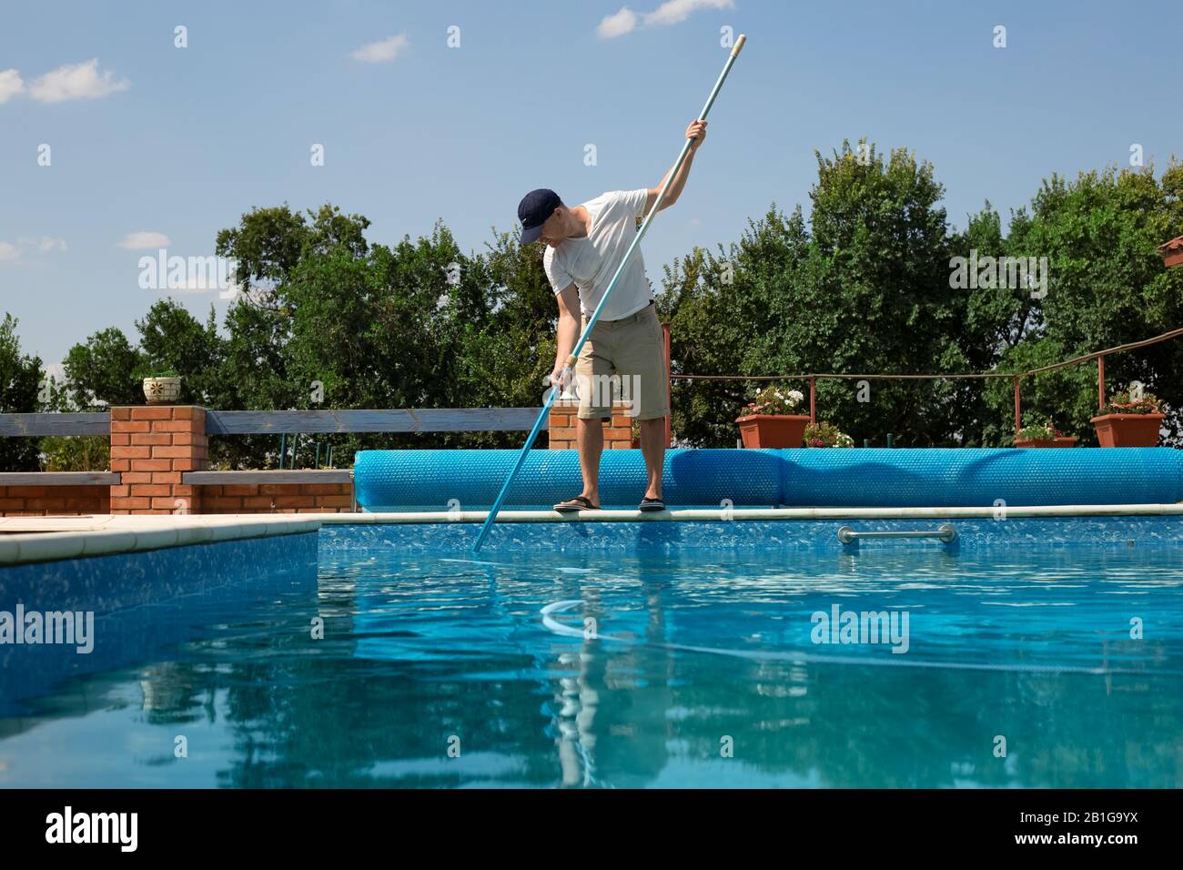 Pulizia della piscina. Man pulizia piscina esterna con aspirapolvere in estate. Preparazioni stagionali.sistemi di pulizia per Foto Stock