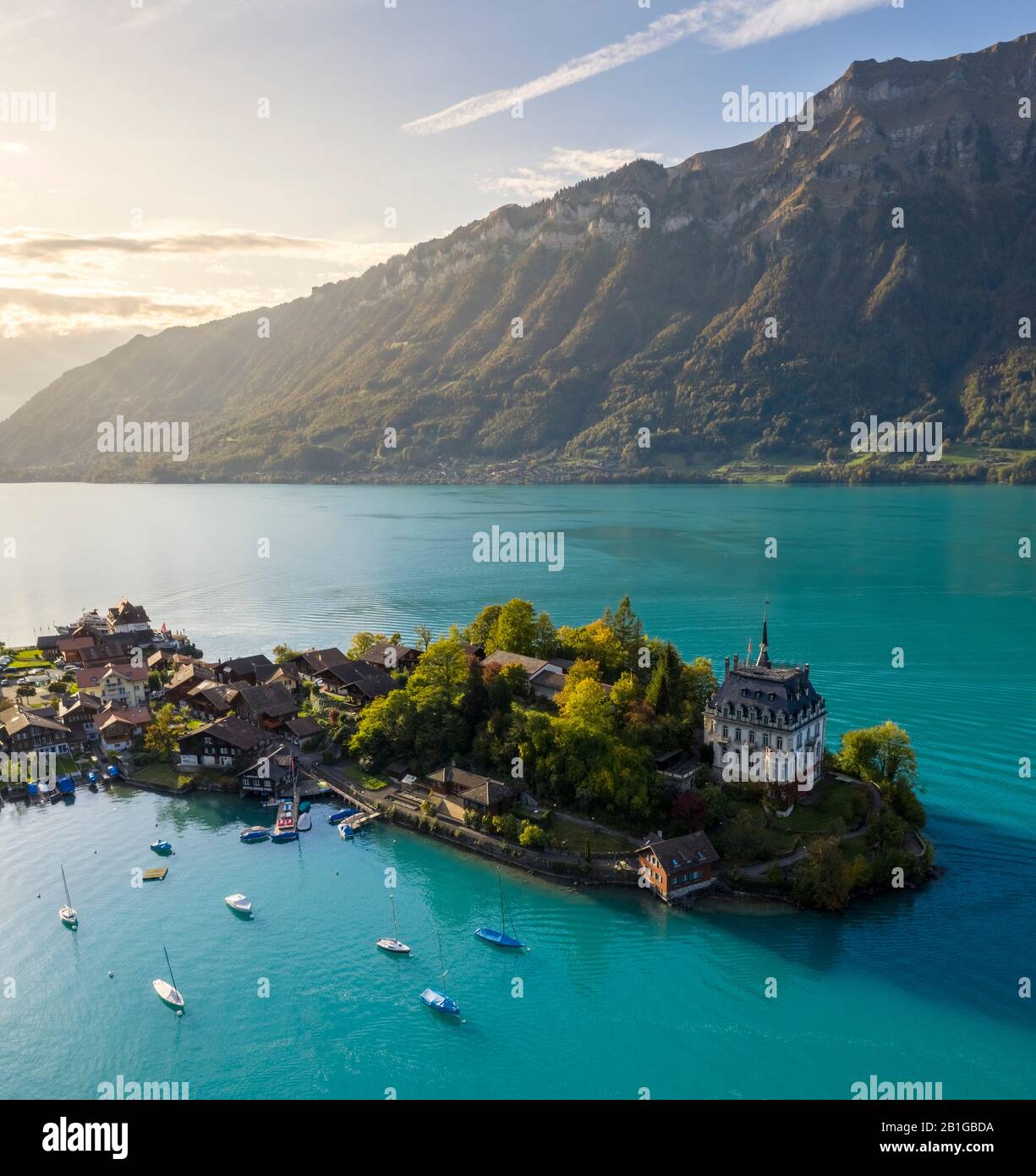 Veduta aerea del villaggio di Iseltwald e della sua penisola con il vecchio Castello durante un tramonto autunnale sul Lago di Brienz. Foto Stock