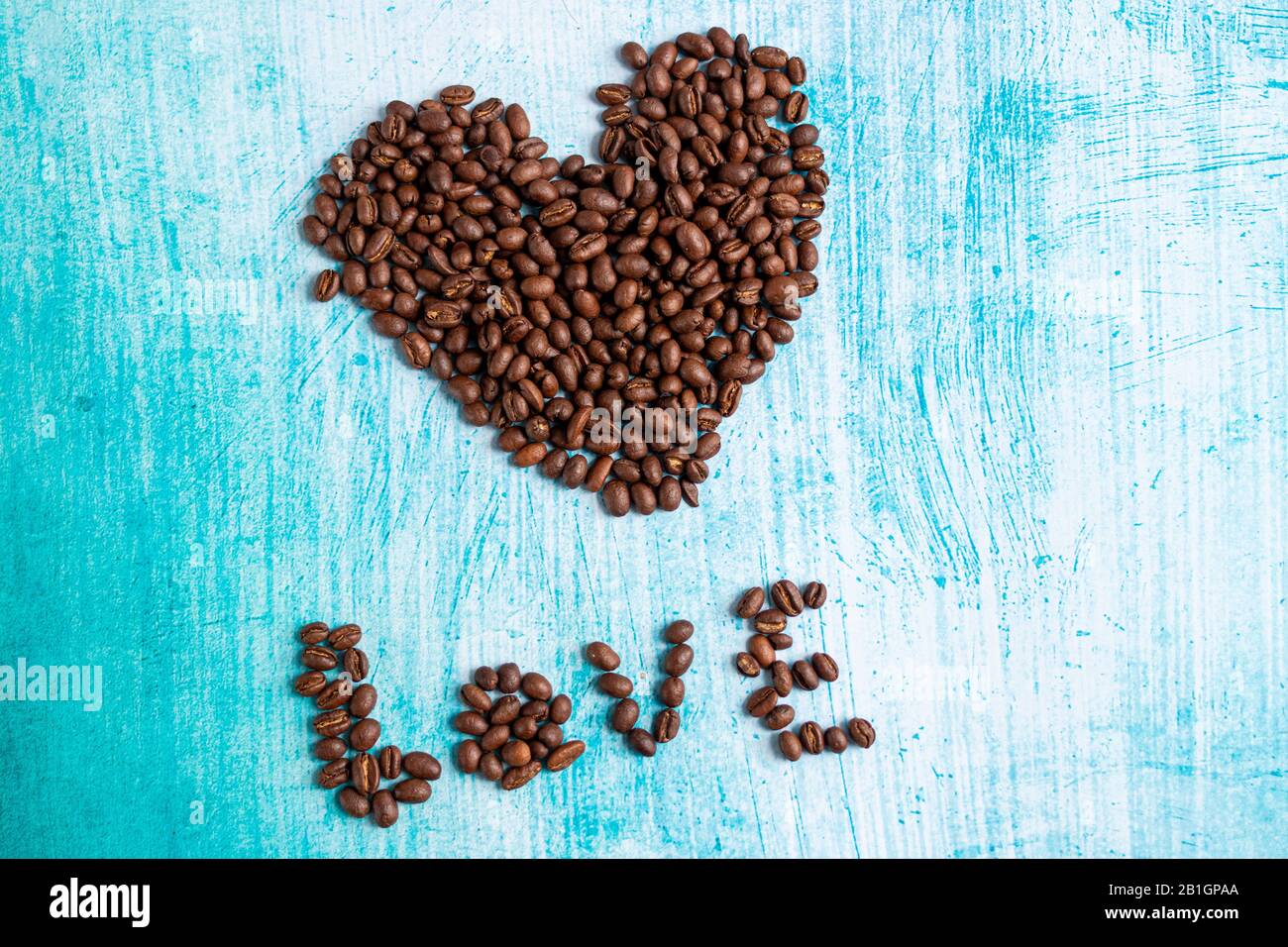 Grani di caffè a forma di cuore su sfondo acquamarina Foto Stock