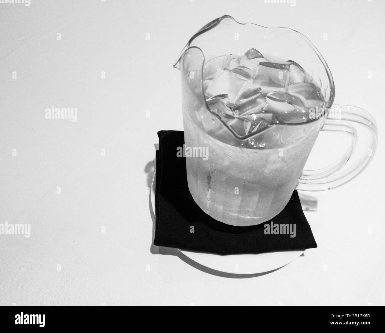 Caraffa con acqua fredda e cubetti di ghiaccio sul tovagliolo da tavolo. Foto Stock