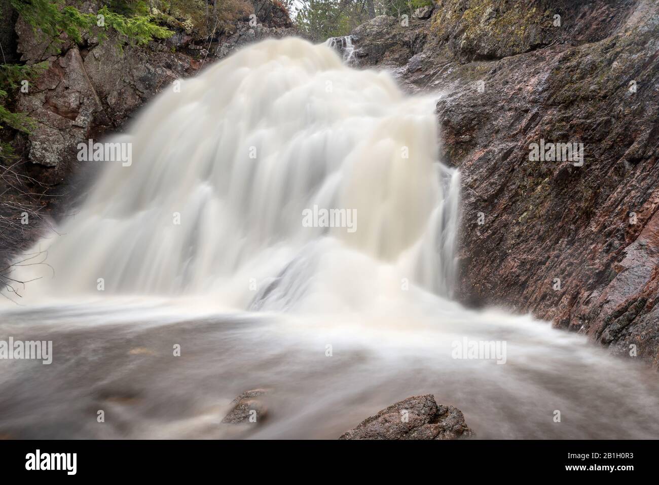 Lunga esposizione di una cascata tipo velo nuziale. La lunga esposizione produce un effetto nebbia per l'acqua. Roccia intorno all'acqua. Foto Stock