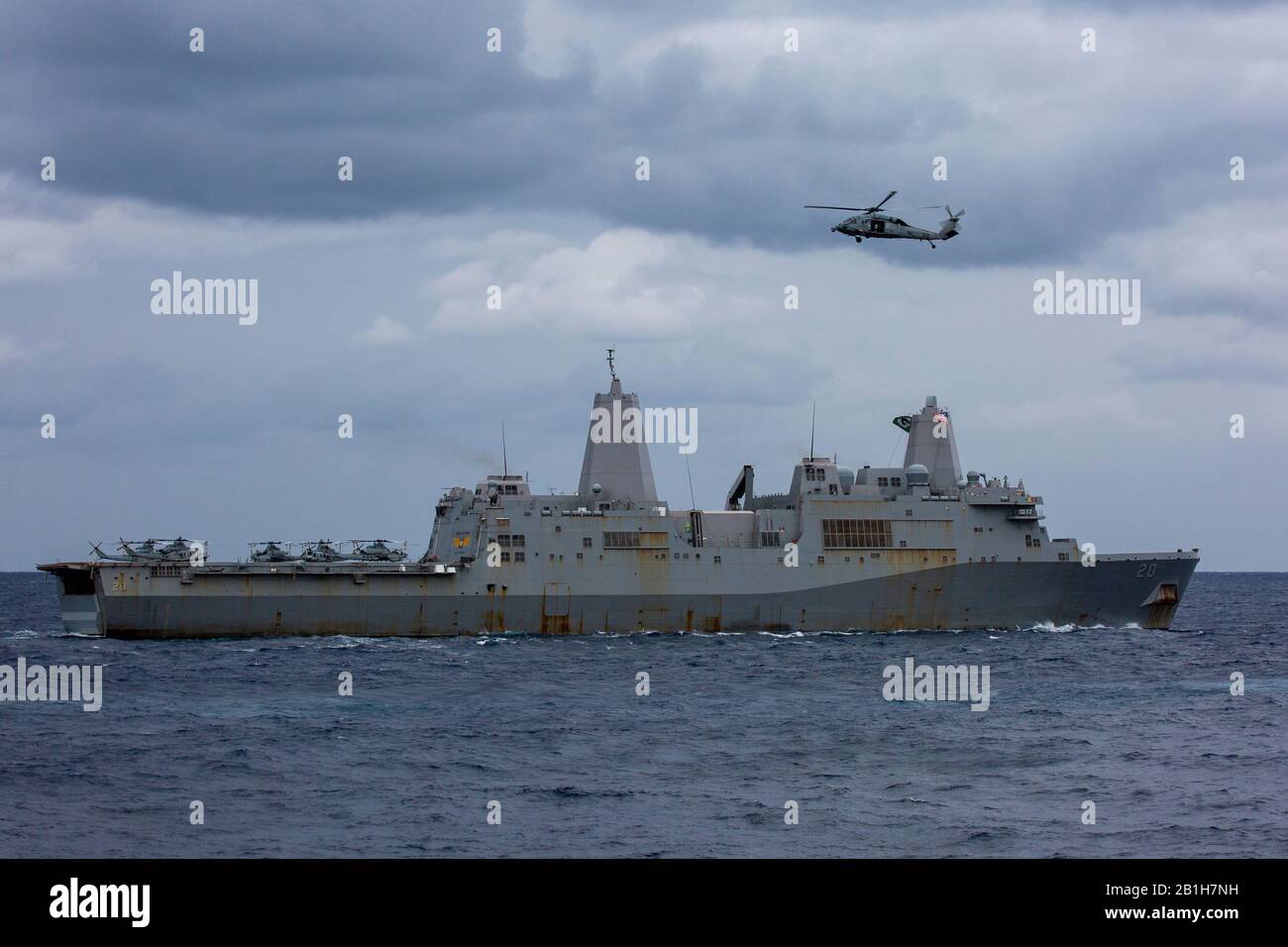 Philippine MARE (Gen. 29, 2020) Il molo di trasporto anfibio USS Green Bay (LPD 20) transita nell'oceano aperto mentre un MH-60S Seahawk con la 'Island Knights' di Helicopter Sea Combat Squadron 25 vola in alto. Greenbay, parte dell'America Expeditionary Strike Group, 31st MEU team, opera nell'area di operazioni della 7th Fleet degli Stati Uniti per migliorare l'interoperabilità con alleati e partner e servire come forza di risposta pronta per difendere la pace e la stabilità nella regione indo-pacifica. (Foto ufficiale del corpo Marino degli Stati Uniti di Lance Cpl. Joshua Sechser) Foto Stock