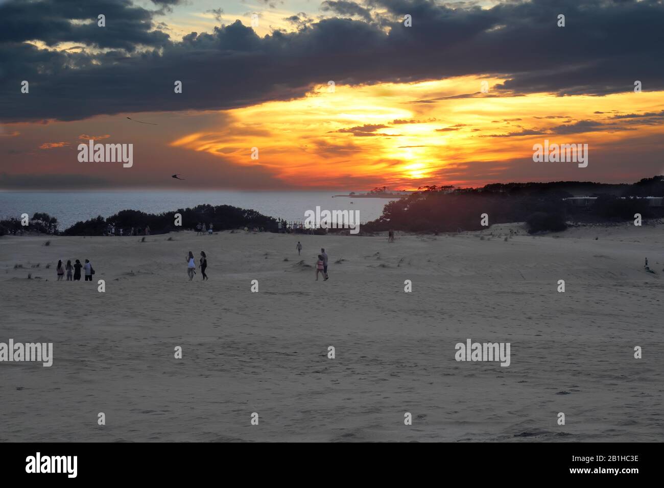 Le persone che volano i aquiloni e che guardano il sole tramontano il suono di Albemarle al parco statale di JockeyÕs Ridge, il più alto Foto Stock