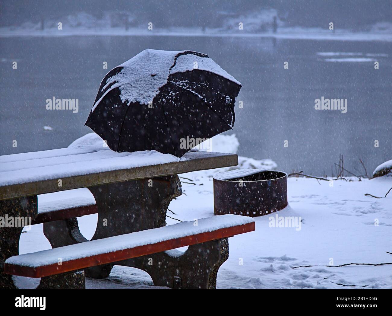 L'ombrello innevato poggia sul tavolo da picnic durante la tempesta di neve Foto Stock