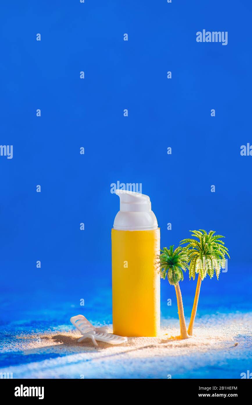 Concetto di skincare estivo con tubo solare e palme in miniatura, sfondo blu con spazio copia Foto Stock