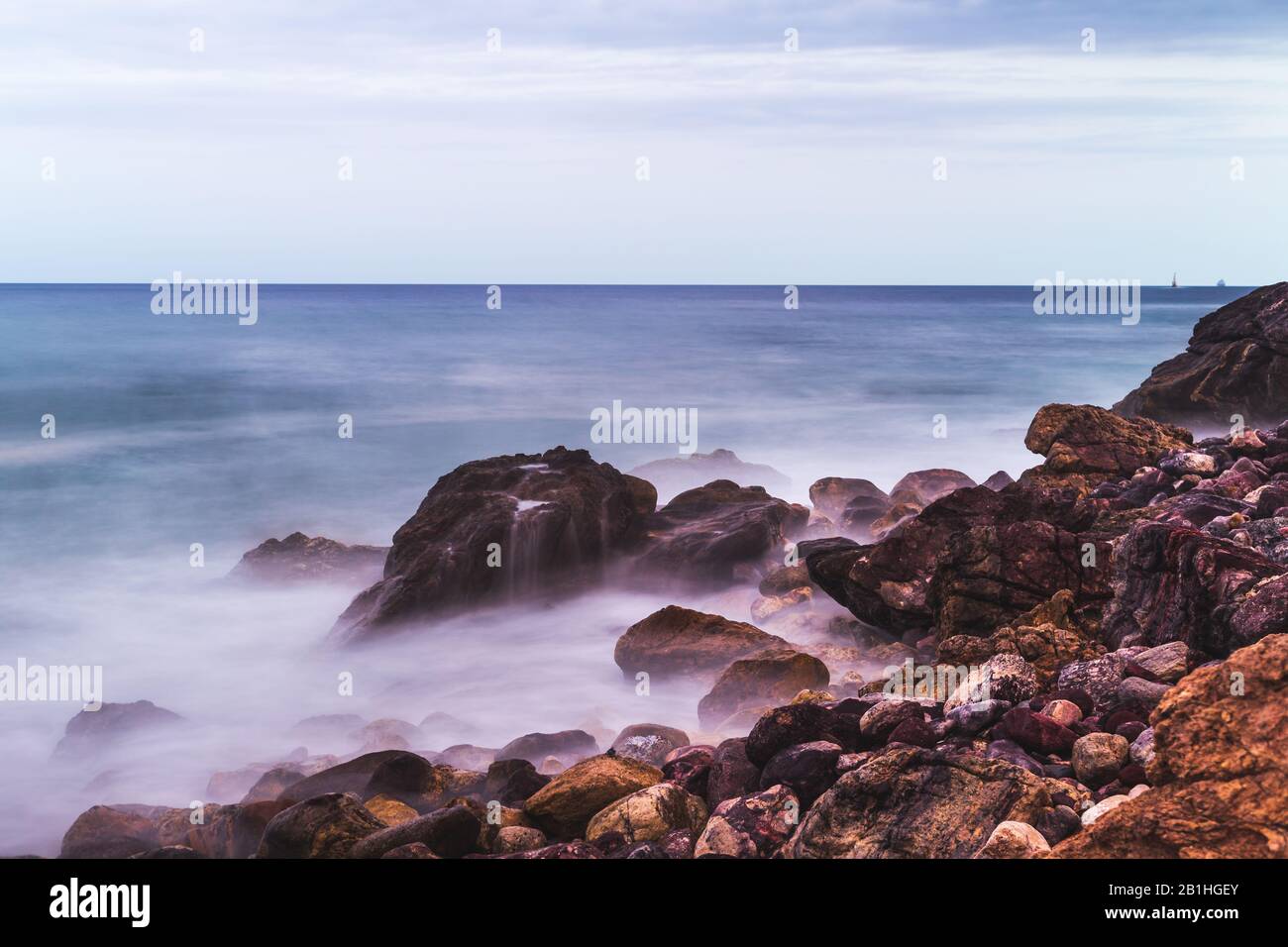 Lunga esposizione foto del mare, dove le onde si infrangono sulle pietre a Mazatlan Foto Stock
